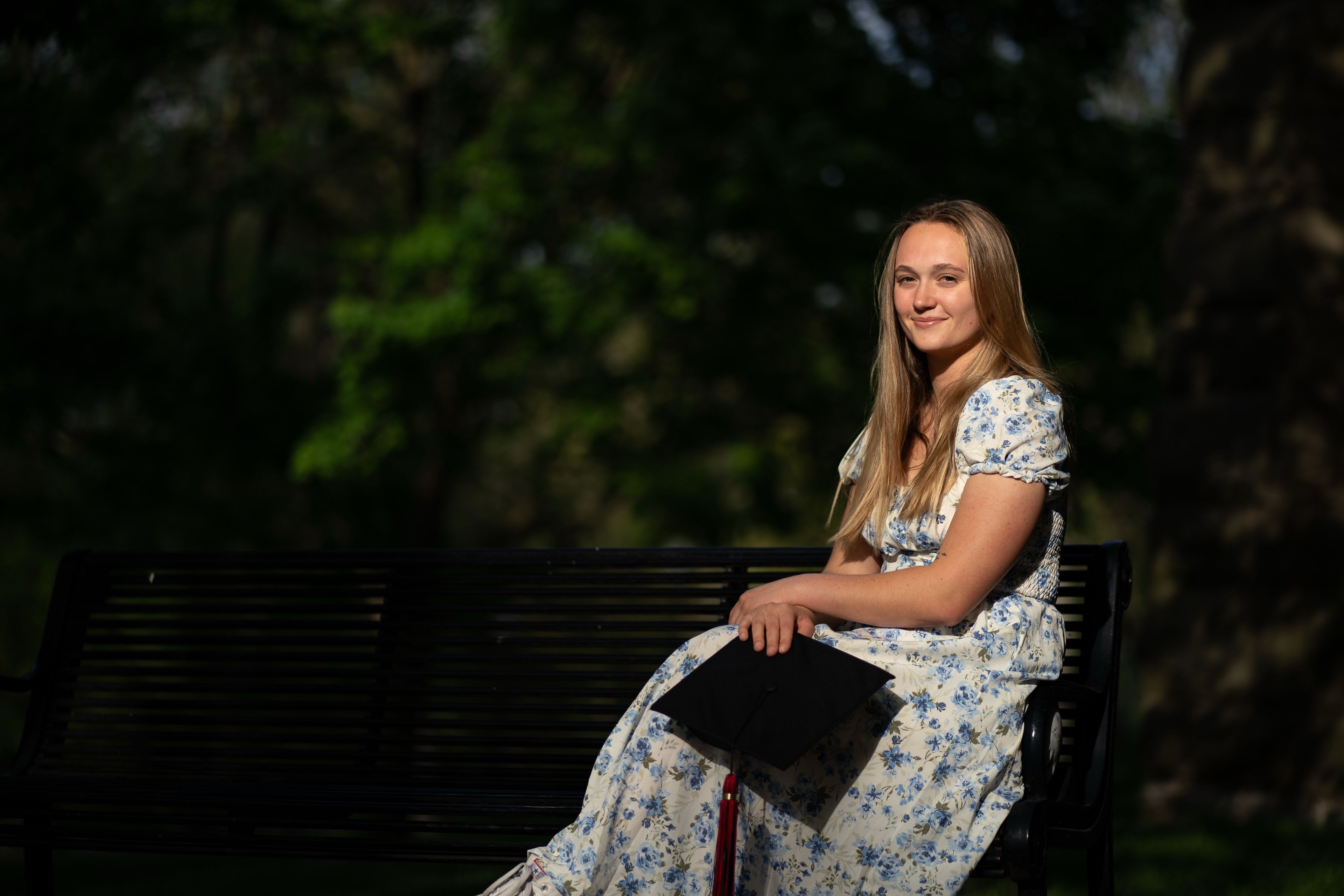 Senior portrait on park bench at golden hour